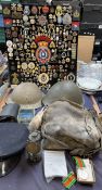 A display of military cap badges, pin badges etc together with steel helmets, gas mask,