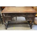 An oak desk with a leather inset top and four drawers on cup and cover legs united by a stretcher