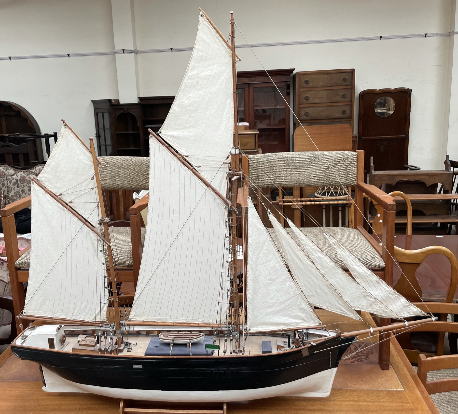 A model ship, with two masts and sails unfurled, on a stand,