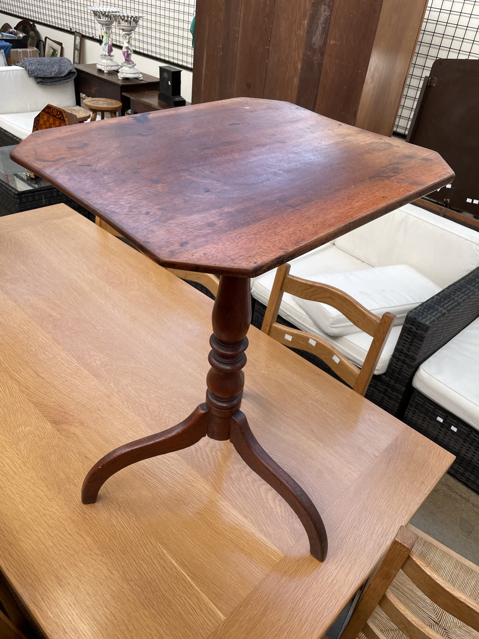 A 19th century mahogany tripod table with a rectangular top with cut corners on a baluster column