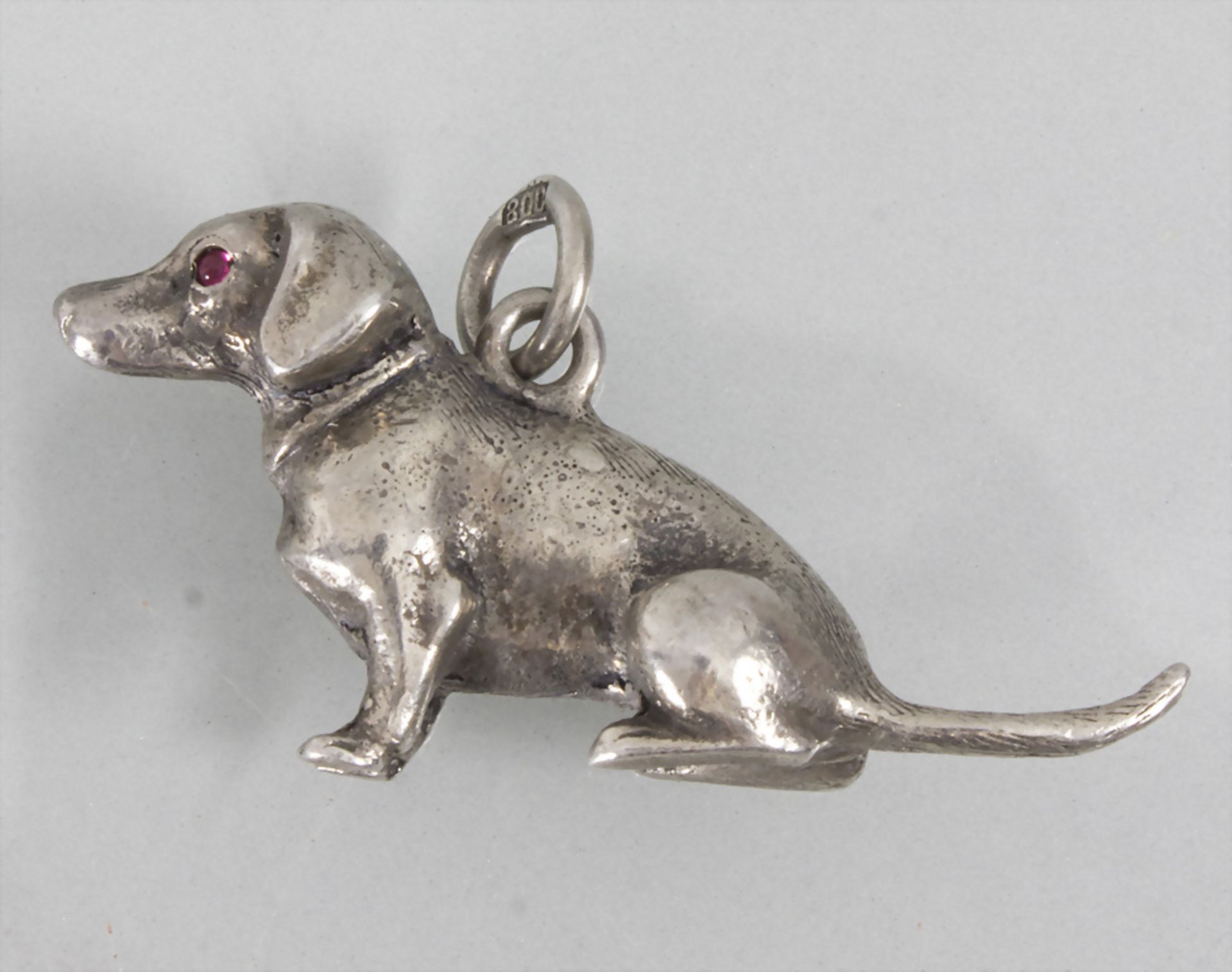 Silberanhänger 'Sitzender Dackel' / A silver pendant 'dachshund' with rubies, um 1900