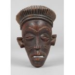 Gesichtsmaske Westafrika, 20. Jh., Tropenholz beschnitzt, rot und braun gefasst, mit geschnitzten