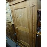 A modern pine hanging wardrobe with panelled door above a drawered base, another similar but smaller