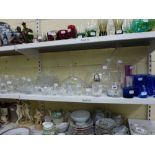 Two shelves of glass ware including dessert bowls, vases, trays, mugs, decanters, wine glasses,