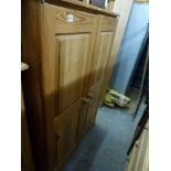 A pine wardrobe with hanging behind two panel doors. TO BID ON THIS LOT AND FOR VIEWING APPOINTMENTS