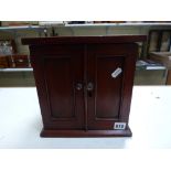 A coin collector's cabinet, of 13 drawers enclosed by a pair of doors, possibly in teak, 10.25 in