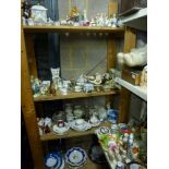 Four shelves of ornaments and dinner wares including cat figurines, trinket boxes and covers, cherub
