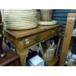 A reproduction cross-banded walnut writing table, the drawer above a shaped frieze on carved