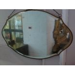 An early 20th century shaped oval and bevelled wall mirror in a gilt metal frame with ribbon