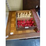 An antique chess set in carved bone, natural and red-stained, in wooden box, with two marquetry