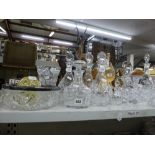 A shelf of glassware including a set of three matching decanters and stoppers, four further