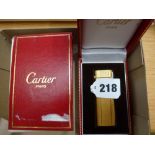 A gilt metal gas lighter by Cartier of Paris in original box. TO BID ON THIS LOT AND FOR VIEWING