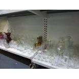 A shelf and a half of glassware including three decanters and stoppers, amethyst glass vase, a