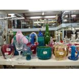 A shelf of coloured glassware including Modena vases, bowls, paperweights, Vaseline glass vase,