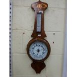 An Edwardian Art Nouveau aneroid barometer, the oak wheel-form backboard inlaid in copper and