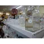 A shelf of glassware including seven decanters and stoppers five with spirit labels, jugs, sherry