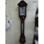 A carved wooden barometer, possibly walnut by W Aronsberg & Co, Manchester [wall next to s77] TO BID