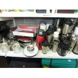Three shelves of mixed kitchenwares including storage canisters, insulated coffee mugs, thermos