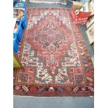 A large Eastern rug woven with a bold pink and red pole medallion on a cream field [floor by