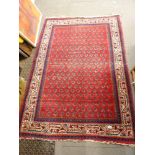 An Eastern rug woven with botehs on a crimson field, cream main border [by silver-plate] TO BID ON