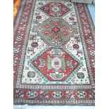 A small rug, possibly Iranian, with central medallions on a cream ground with claret outer