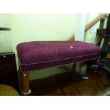 A very smart and modern rectangular footstool upholstered in plum coloured velvet with multi-