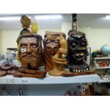 A collection of carved wooden heads, large wooden spoons and an African carved wood table lamp [