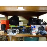 A shelf of mainly cameras including a Canon EOS 350D with lens, a Panasonic Lumex DMC-TZ5, a Canon