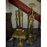 Two sets of brass fireside implements, a stone and metal poker, a brass trivet, a toasting fork