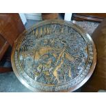 An Eastern circular coffee table the top heavily carved with scenes of fishermen, pagodas and