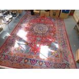 An Iranian carpet with central blue medallion on red ground with multiple floral decoration. [