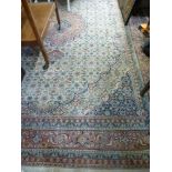 A woollen carpet square in the Persian style with a central floral cartouche in pink and blue on a