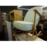 An Ercol light oak rocking chair with a modern blue and gold fabric cover. WE DO NOT TAKE CREDIT