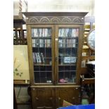 An oak library bookcase on a cupboard base with carved decoration, a narrow oak dining table that