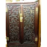 A 19th century hardwood Chinese cabinet each panel door elaborately carved with dragons chasing