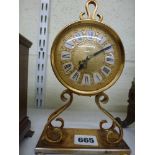 A 1950s Imhof Swiss mantel timepiece in gilt-metal on scroll supports, 8 in high [A] WE DO NOT