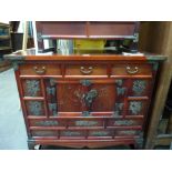 A small low Chinese cabinet with three small drawers above a cupboard with butterfly hinges to the