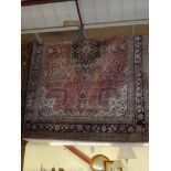 A woollen rug decorated in the Persian style with foliage and flowers on a pink ground with floral