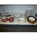 A shelf of porcelain tableware, including six Wedgwood blue and gold soup plates and six matching