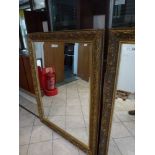 A large pair of gilt framed mirrors with bevelled edges and floral decoration WE DO NOT TAKE