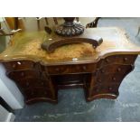 A Victorian knee-hole desk of dramatic form, the shaped break-front top inset with a green leather