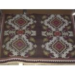 A large rug with kelim style decoration of large diamonds each within a white border on a green main