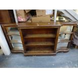 An unusual Victorian walnut shallow bookcase of three shelves flanked by mirrored display shelves of