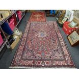 An Eastern carpet of traditional design the multiple floral decoration on a red ground within a