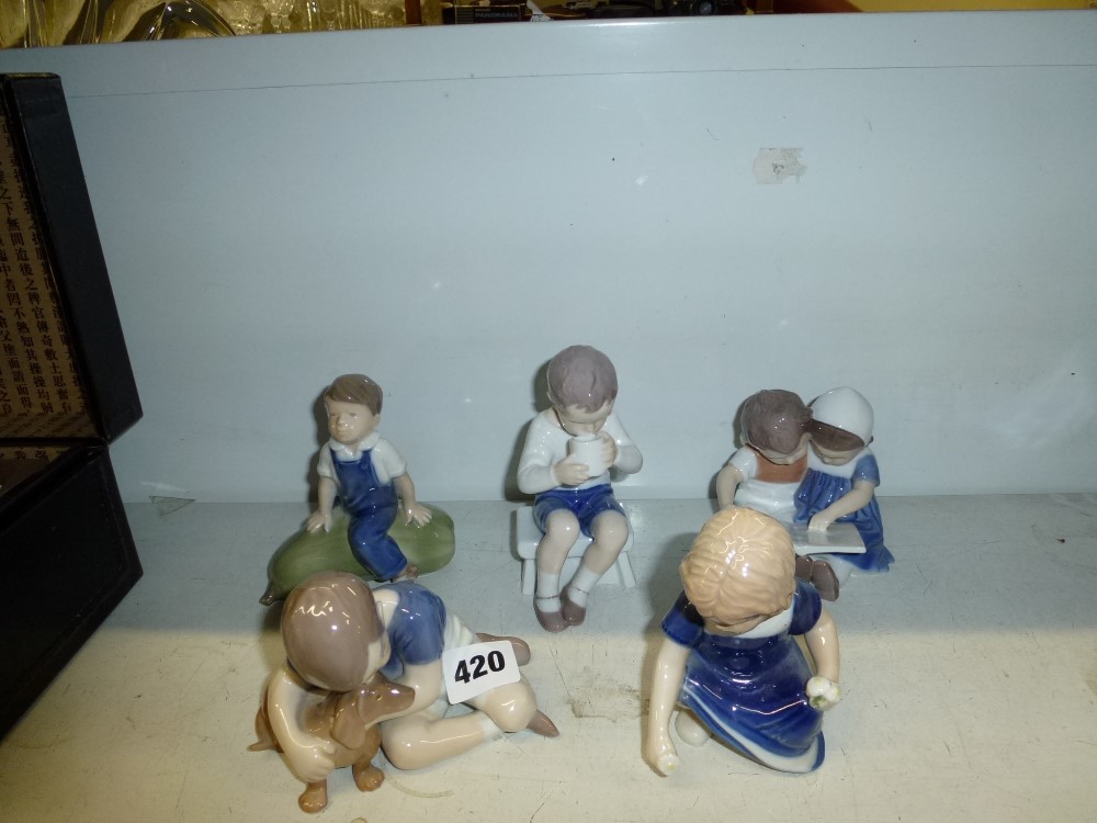 Five Royal Copenhagen figurines of children variously sat reading, drinking tea, cuddling a dog,