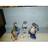 Five Royal Copenhagen figurines of children variously sat reading, drinking tea, cuddling a dog,