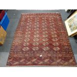 An early 20th century small Bokhara rug of traditional design on claret ground. [floor by