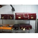 A burgundy leather suitcase and matching overnight case, both with combination locks, a similar