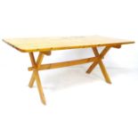 A pine kitchen table, mid to late 20th century, with X frame trestle base, 90 by 183 by 76cm high.