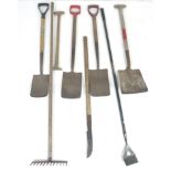 A group of garden tools, comprising four spades, a hoe, a rake, a garden slasher, and a wooden